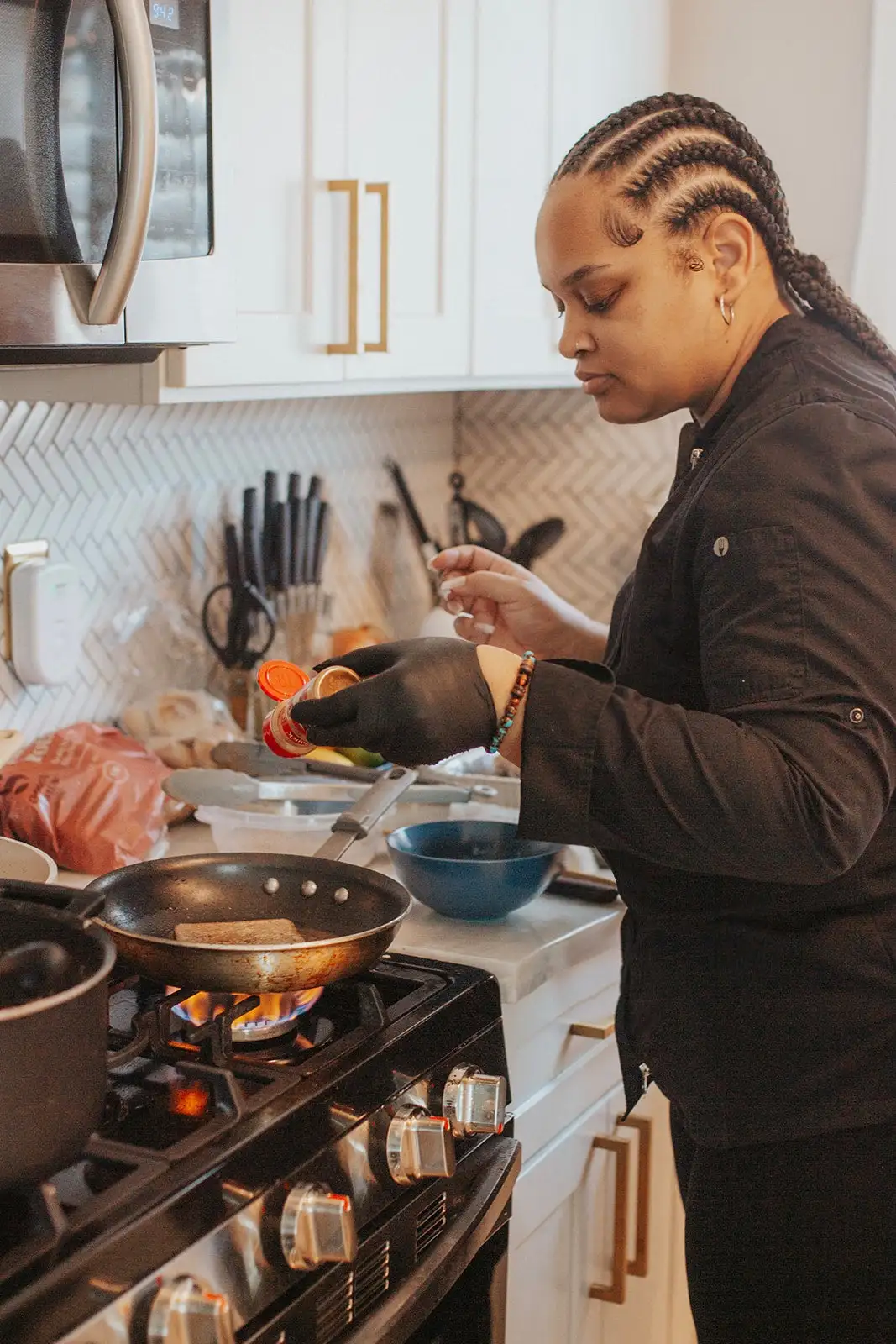 Chef Bree seasoning a pan over a lit gas burner